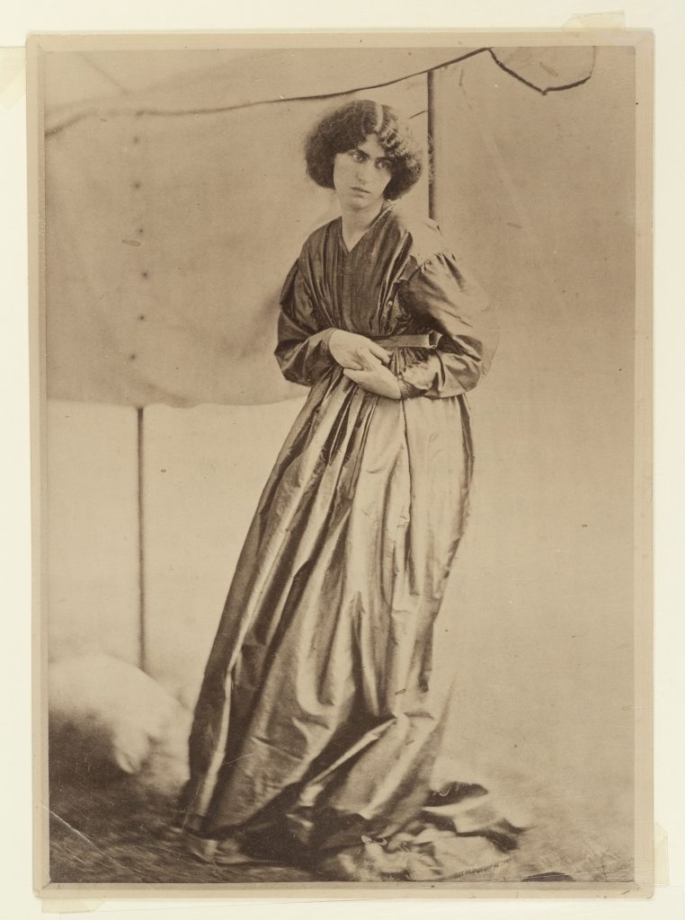 Jane Morris standing against an awning, 1865