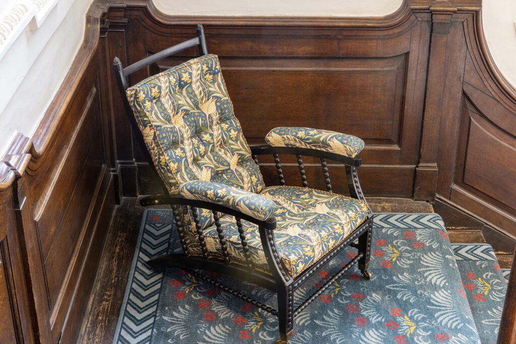 Morris & Co armchair with upholstered and padded armrests and seat cover.