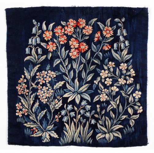 Woven tapestry in wool depicting blue bells and other flowers on a dark blue ground