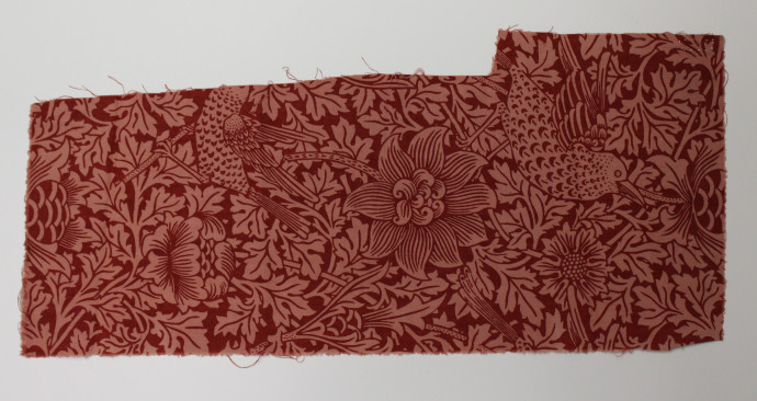 Sample of fabric featuring a floral design in red with rows of birds.