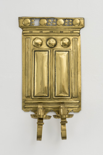 A brass candle sconce with pierced work stars and a sun motif, designed to hold two candles