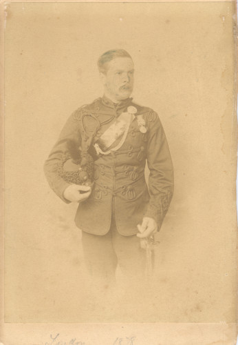 A man wearing a military uniform holding a ceremonial sword and helmet