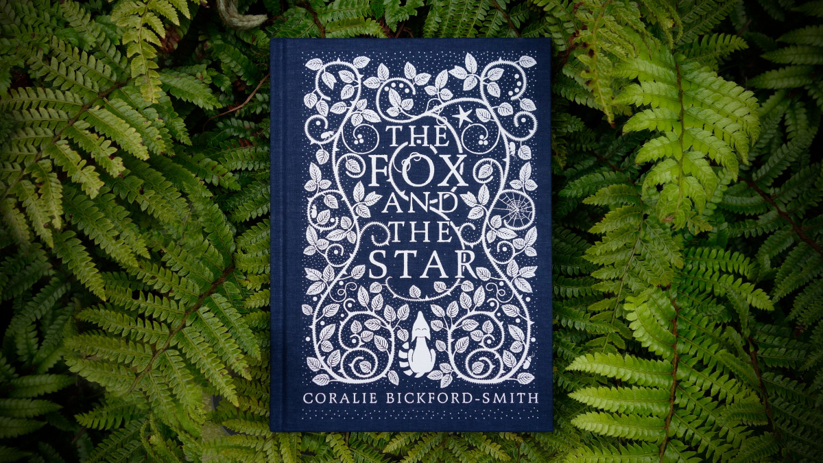 The cover of The Fox and the Star photographed from above, sitting on the leaves of green ferns