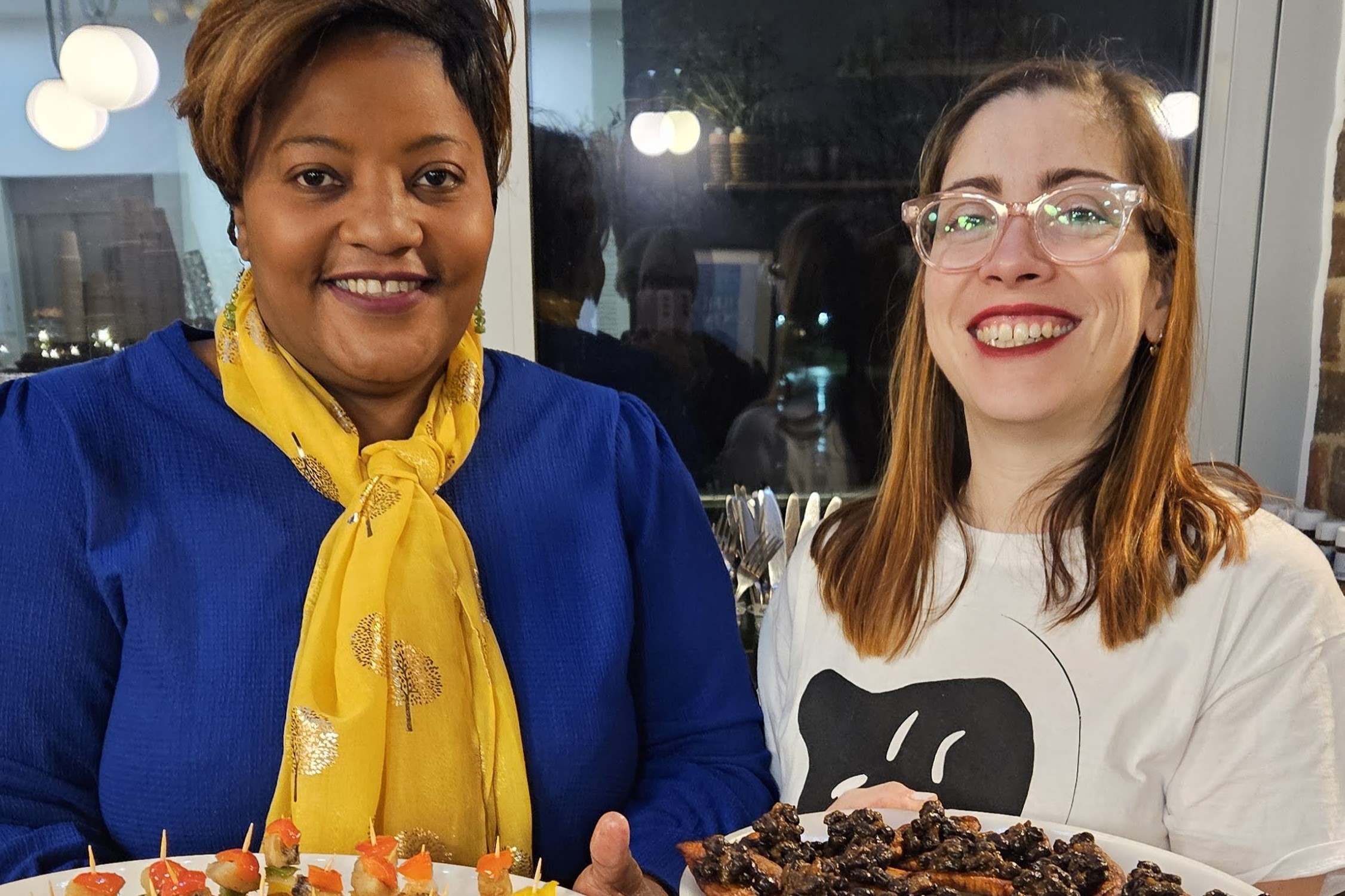 Two people presenting trays of food at a gathering